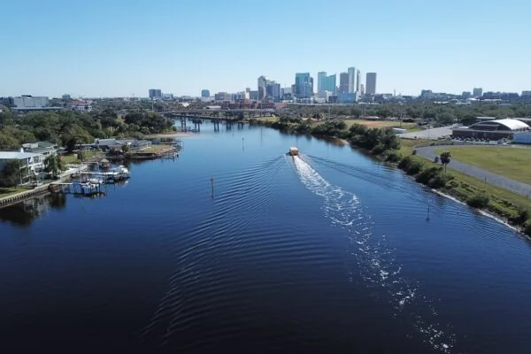 white boat on body of water near city buildings during daytime