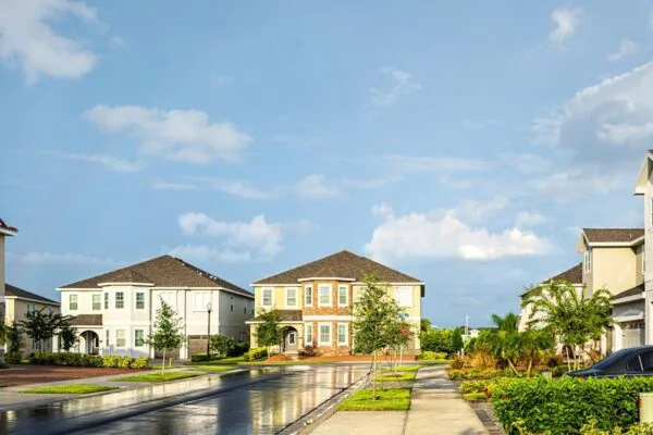 white and brown house near green trees under blue sky during daytime