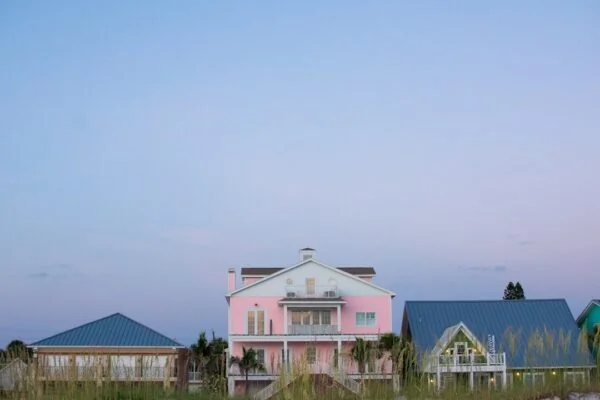 A pink house sitting on top of a lush green field