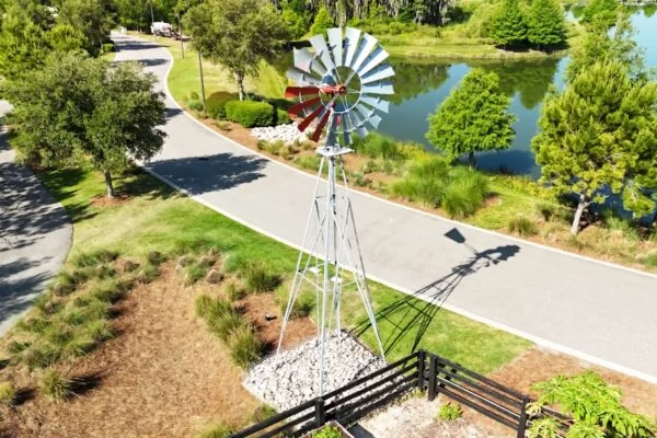 a windmill on the side of a road next to a lake