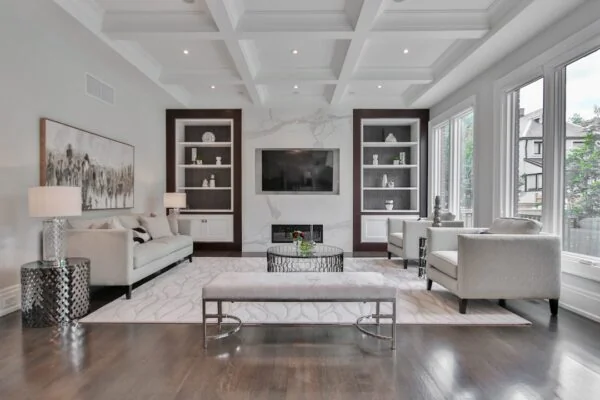 A living room with a marble fireplace, white sofas, and dark wood shelving